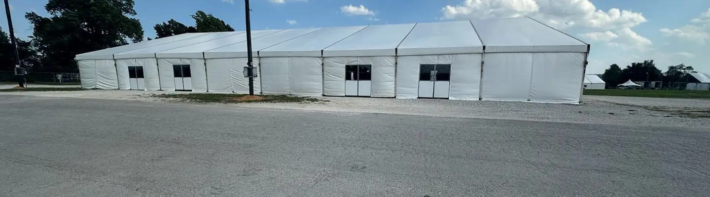 Construction of a fabric structure with a metal frame and a crane in a field, showcasing eco-friendly building practices.