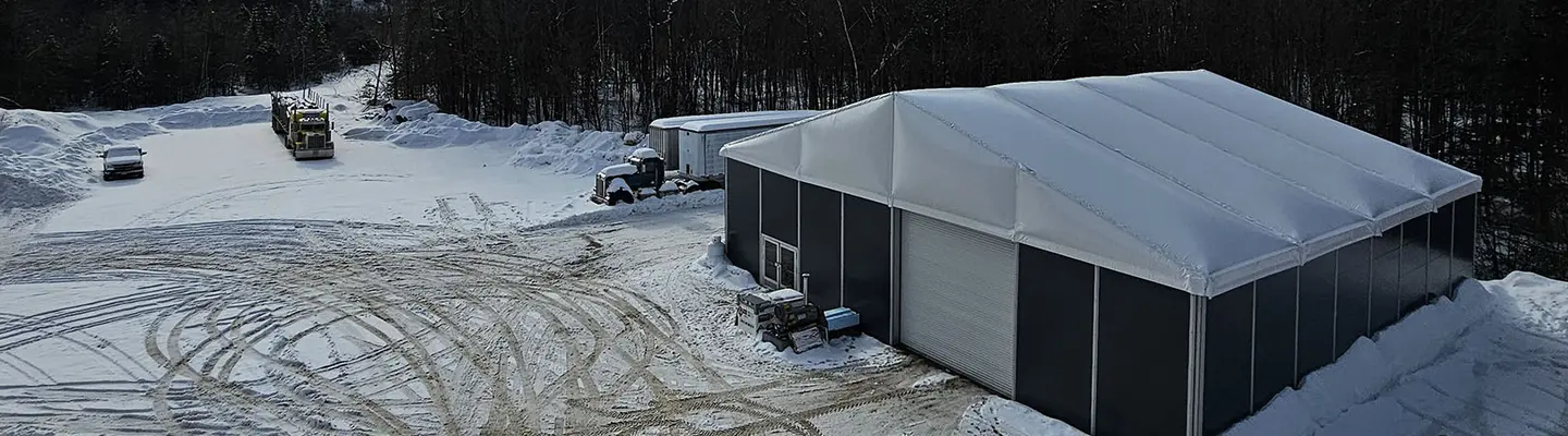 Large construction tent in a snowy outdoor environment, showcasing its durable vinyl cover and climate-controlled design.