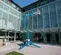 Rear angled view of a blue Genie boom lift with basket outdoors elevated to clean exterior glass windows on a building.