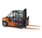 Side view of an orange and black Toyota warehouse forklift with a black mast and orange forks with an enclosed cabin.