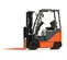 Side view of an orange and black Toyota warehouse forklift with a black mast, orange forks and an open cabin.