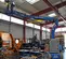 Side view of blue Genie articulating boom lift with extended platform, worker on platform working on light in a warehouse.