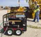 Black and red Mi-T-M 5,000 psi pressure washer being used to wash a piece of heavy machinery
