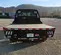 Rear view of a black flatbed truck bed, featuring a diamond plate surface and a tall headboard with an open design.
