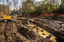 Yellow John Deere excavator digging in the dirt